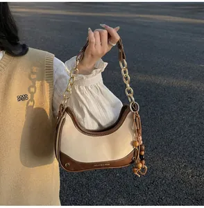 Detail of a chic patchwork shoulder bag featuring gold chain strap and wooden bead tassel