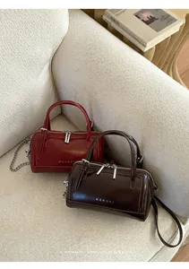 Détail des sacs Boston en cuir ciré bordeaux et café avec le logo argenté MUHSTR