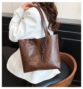 Détail du grand sac cabas en cuir marron avec étiquette mode et pendentif noué