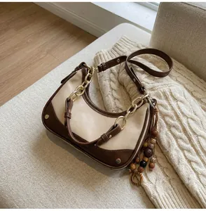 Detail of hobo bag with contrast trim, gold chain strap, and wood bead tassel charm