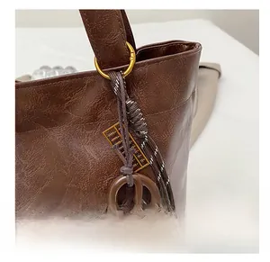 Détail d'une breloque boulier dorée sur corde tressée d'un sac cabas en cuir marron