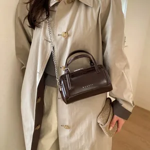 Sac Boston vintage en cuir ciré marron avec logo MUHETA et bandoulière sur un modèle