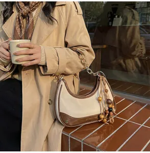 Close-up of contrast-colored shoulder bag with gold chain and wooden bead tassel details