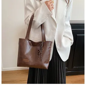 Sac fourre-tout marron foncé avec texture brillante et étiquette fashion sur un mannequin