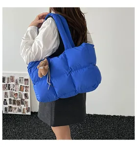 Μπλε καπιτονέ τσάντα puffer με μαλακή υφή και κρεμαστό αρκουδάκι πάνω σε μοντέλο