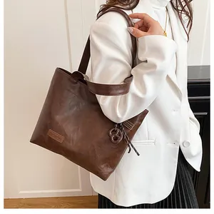 Sac cabas marron en similicuir avec étiquette FASHION, porté comme un sac à bandoulière chic