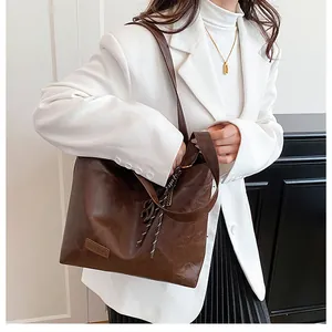 Détail du sac cabas marron vintage avec étiquette mode et cordon à pompons