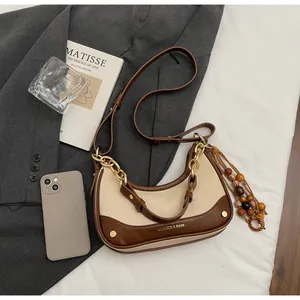 Detail of contrast color beige and brown crescent bag with wooden bead tassel charm