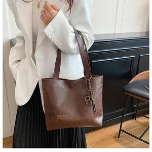 Détail du sac cabas marron foncé avec texture cuir brillant et accessoire tressé