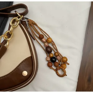 Detail view of contrast color crossbody bag with gold chain and wooden bead charm