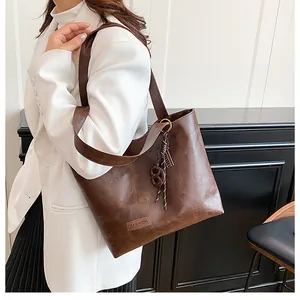 Gros plan d'un grand sac cabas marron foncé avec étiquette et breloque tressée