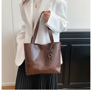 Détail d'un grand sac cabas marron en similicuir avec étiquette mode et anse tressée