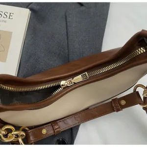 Close-up of golden zipper hardware and contrast leather on a chic chain square bag