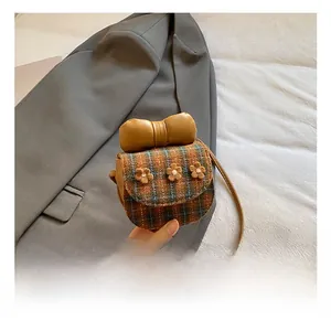 Detail shot of mini plaid crossbody bag with 3D floral accents and a brown leather bow
