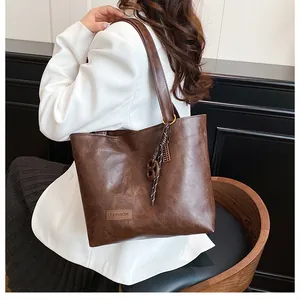 Détail du sac cabas en cuir marron foncé avec étiquette FASHION et bandoulière tissée