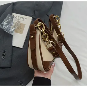 Detail view of the two-tone cream and brown crossbody bag with gold chain strap