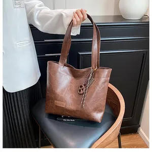Détail d'un sac cabas marron vintage avec étiquette en cuir et pendentif tressé chic