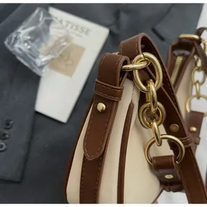 Detail of beige shoulder bag showing leather stitching and gold-tone chain hardware
