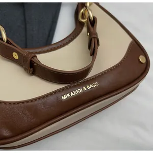 Detail of contrast stitching, gold metal hardware, and premium leather on small square bag