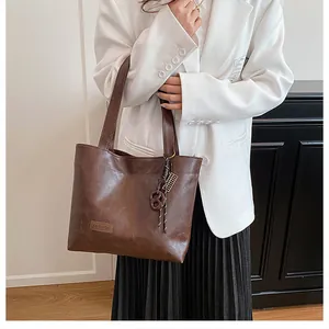 Gros plan sur un sac cabas vintage en cuir marron foncé avec pendentif de mode