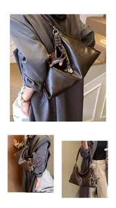 Détail du sac à bandoulière en cuir marron foncé souple avec des breloques élégantes