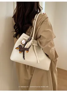 Minimalistische beige Tragetasche mit Dackel-Anhänger und Baseball-Detail im Fokus