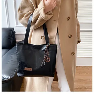 Détail du cabas noir avec une étiquette en cuir et un accessoire en corde tressée