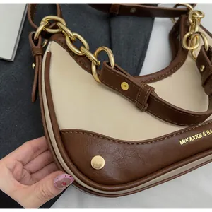 Detail of crescent shoulder bag with gold chain and brown leather contrast trim