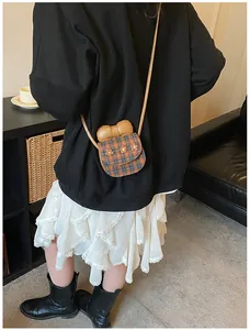 Girl wearing a cute plaid crossbody bag with 3D floral accents and a brown bow detail