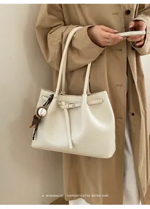 Detailansicht der cremeweißen Ledertasche mit Kieselmaserung und silberner Schnalle
