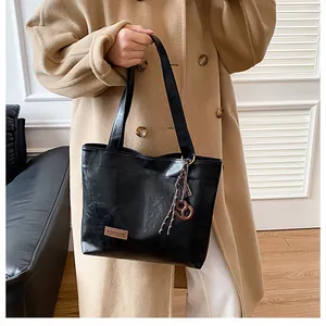 Détail de la texture en cuir PU noir poli et de l'étiquette FASHION sur ce sac cabas