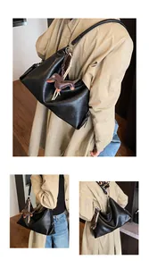 Gros plan d'un sac cabas en cuir noir avec un charm teckel marron et fermeture éclair
