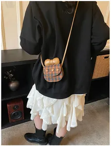 Detail of checkered crossbody bag featuring floral accents and a large beige bow
