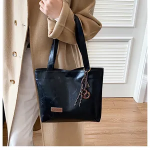 Détail d'un sac cabas noir en similicuir avec étiquette mode et breloque à pompon