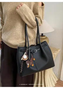 Schwarze Shopper-Tasche aus genarbtem Leder mit Dackel-Anhänger und Baseball-Deko im Alltag
