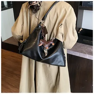 Détail d'un grand sac cabas en cuir souple noir avec un charmant pendentif teckel