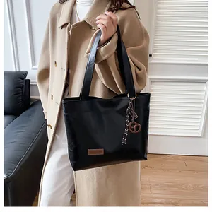 Vue détaillée du cabas noir avec étiquette Fashion et ornement tissé sur la poignée