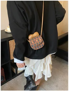 Detailed back view of a mini plaid crossbody bag with a bow and floral accents on a model