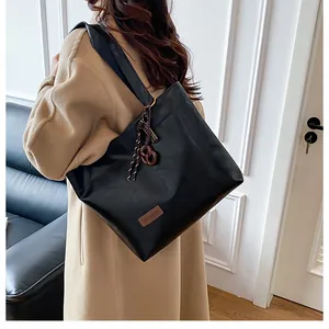 Détail d'un sac cabas noir avec étiquette mode et pendentif déco sur la bandoulière