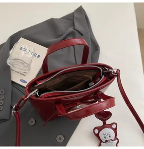 Close-up of the burgundy bucket bag interior with zipper and bear charm detail