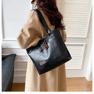 Détail du sac cabas en similicuir noir avec pendentif tressé et étiquette mode