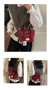Detail view of glossy red patent leather handbag featuring bow and cute bear charm
