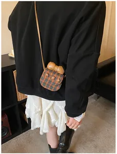 Detail of cute mini checkered crossbody bag with brown bow and floral accents