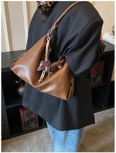Détail du sac à bandoulière marron souple avec pendentif en cuir en forme de teckel