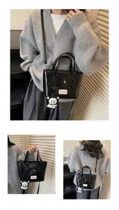 Detail of black glossy handbag with bow, heart pendant and cute bear charm