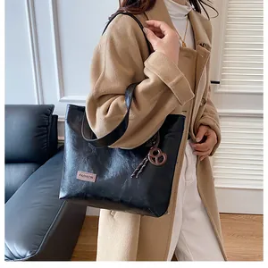 Détail d'un sac cabas noir avec étiquette Fashion et breloque circulaire décorative