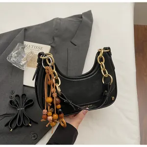 Detail of black moon bag with gold chain strap and wooden bead tassel ornament