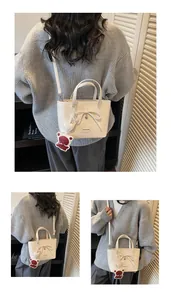 Detail of cream white bucket bag with decorative bow and cute bear charm in close-up