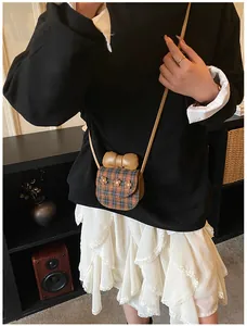 Detail of a mini plaid crossbody bag with a large brown bow and floral accents on a model