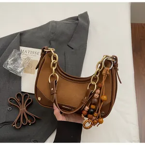 Detail of retro brown half-moon bag with gold chain and wooden bead charm accessory